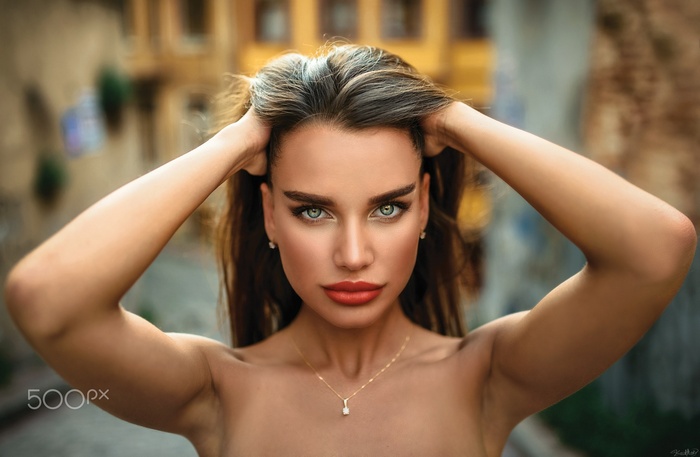 Woman with hands in hair and necklace