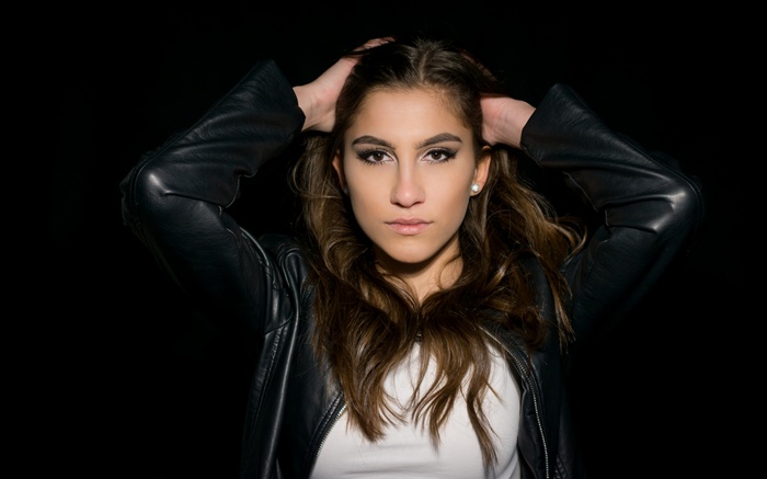 Woman with hands in hair wearing a black leather jacket