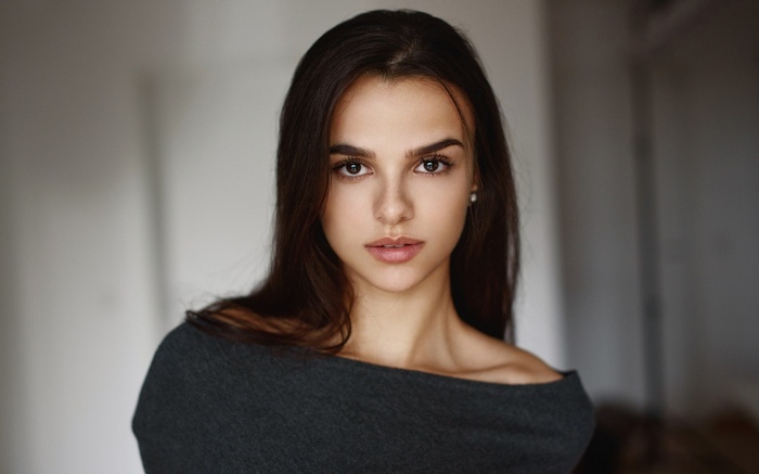Woman with dark hair wearing a grey off-the-shoulder shirt