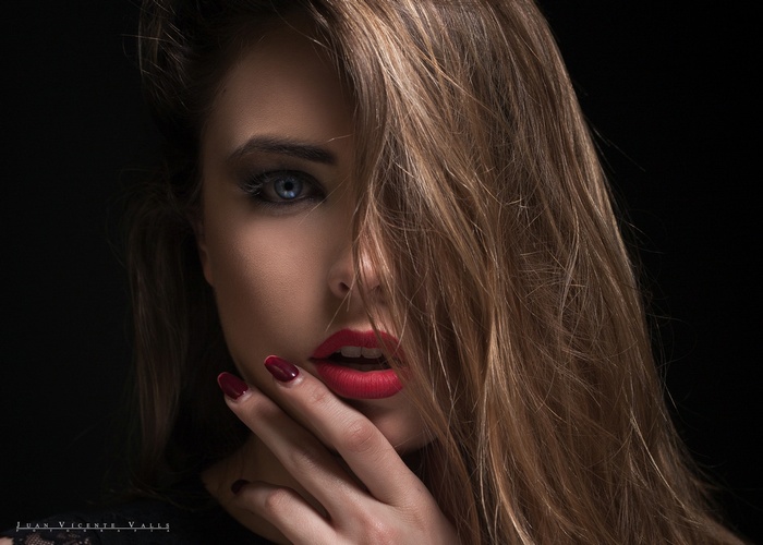 Woman with blue eyes and red lipstick on black background