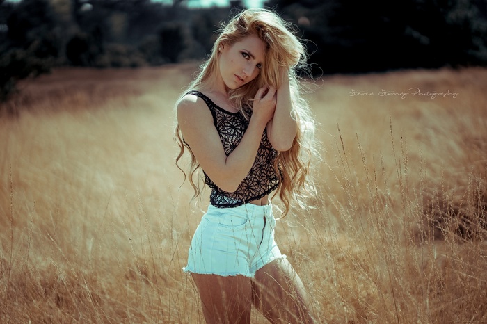 Woman with blonde hair in jean shorts in a field