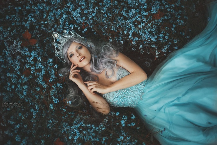 Fantasy girl with crown lying in blue flowers