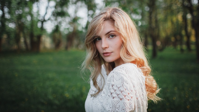 Woman with blonde hair in a white sweater outdoors