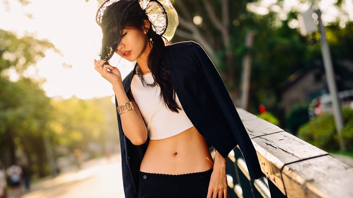 Asian woman wearing a hat and crop top outdoors