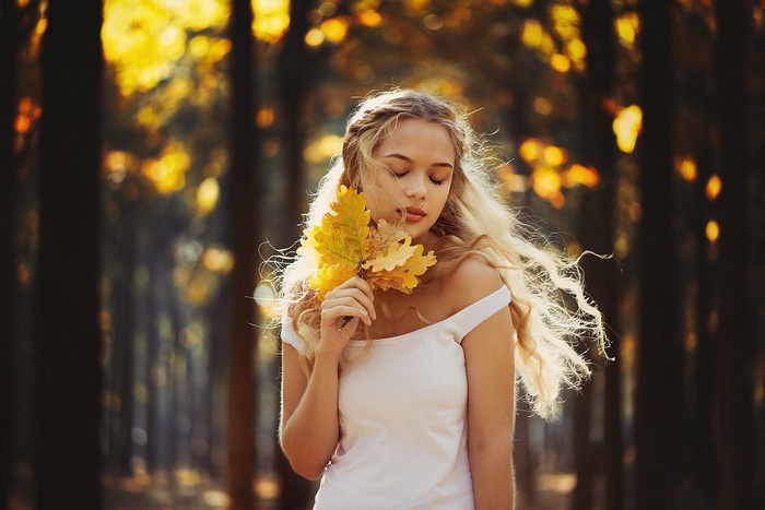 Ann Nevreva holding autumn leaves in a forest