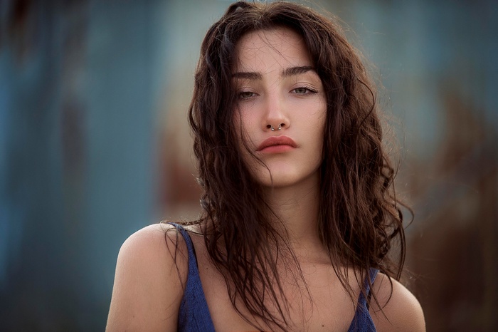 Woman with dark wavy hair and nose ring
