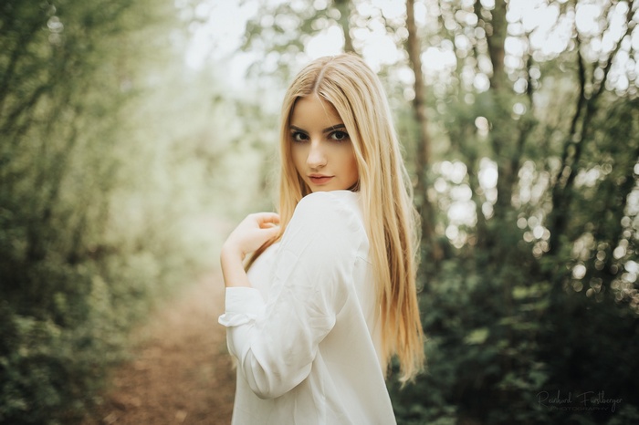 Woman with blonde hair in a white shirt outdoors
