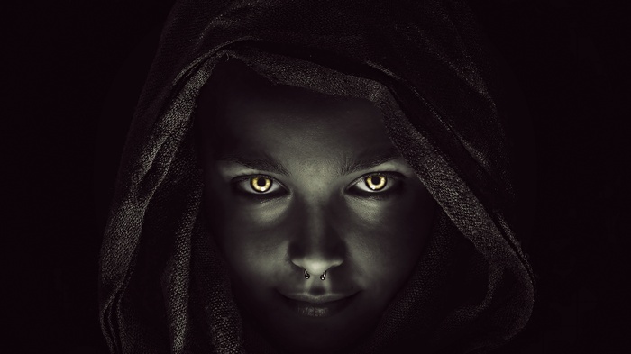 Woman with glowing eyes wearing a hood