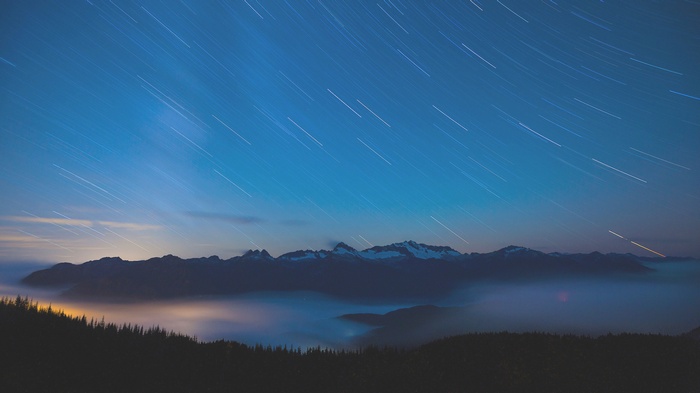 Star trails over misty mountains at night