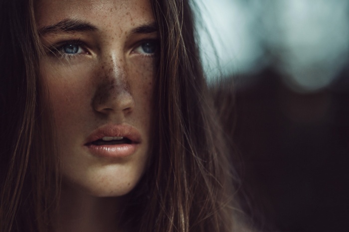 Woman with freckles and blue eyes looking away