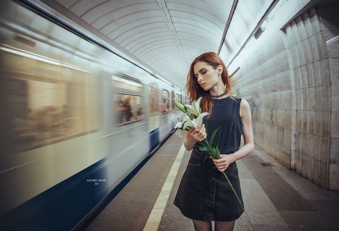 Woman with lilies on a subway platform with a train