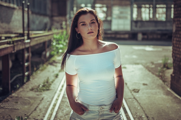 Woman in white off-the-shoulder top and denim shorts outdoors