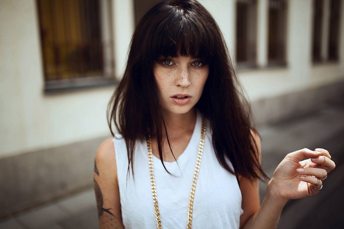 Woman with freckles and tattoo wearing a necklace