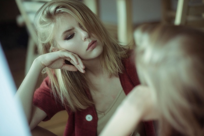 Portrait of a blonde woman looking into a mirror