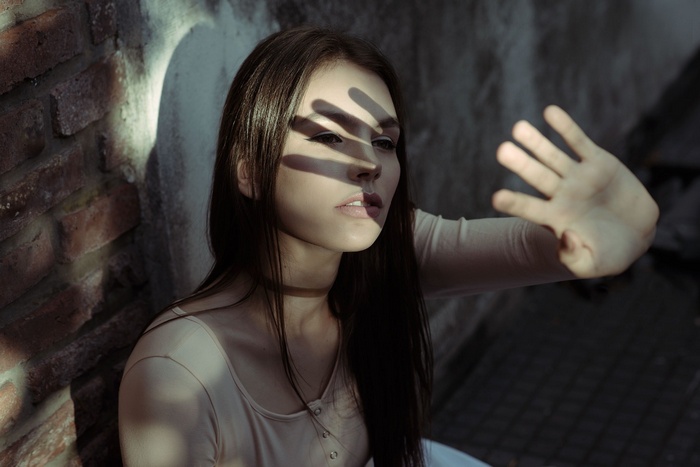 Woman with hand covering face in shadow