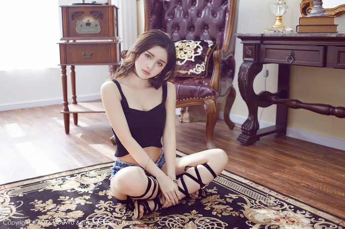 Asian woman wearing choker and shorts sitting on rug