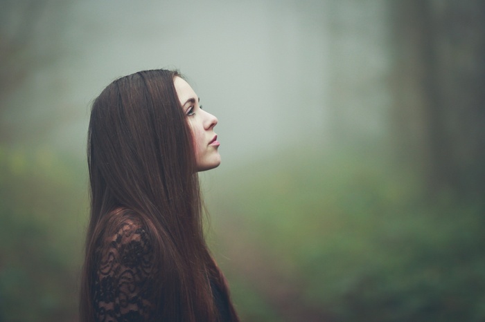 Woman in lace top looking up in foggy forest