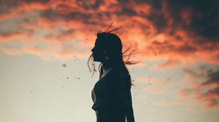 Silhouette of a woman against a sunset sky