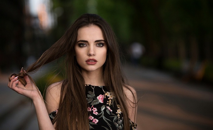 Woman with long brown hair and floral top outdoors