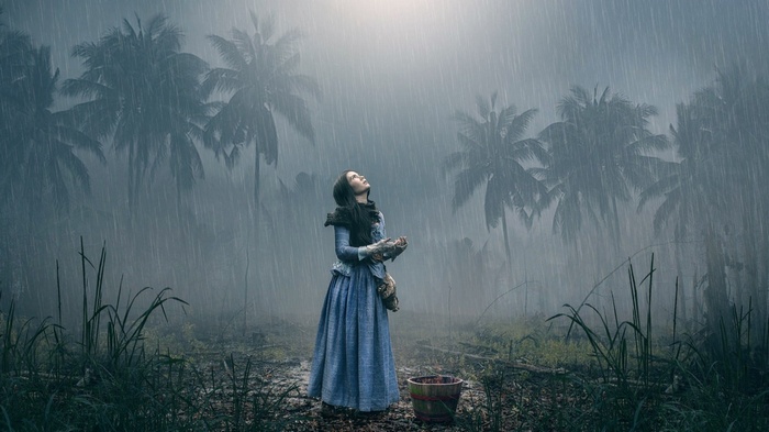 Woman in blue dress looking up in the rain