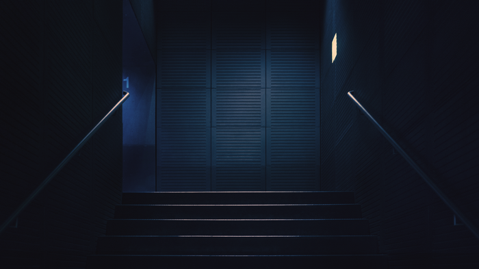 Dark stairway with blue light and handrails