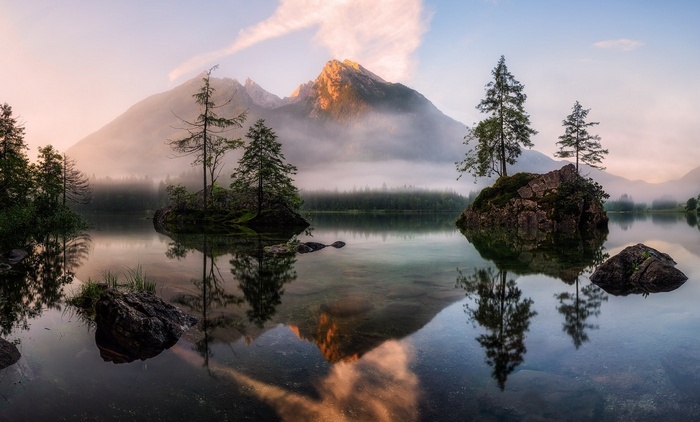 Misty mountains reflected in a calm lake with islands