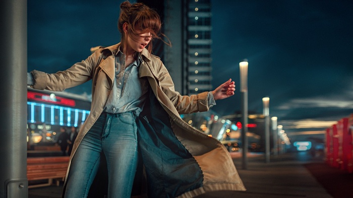 Woman in trench coat and jeans at night