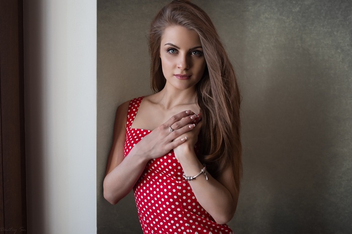 Woman in red polka dot dress by the wall