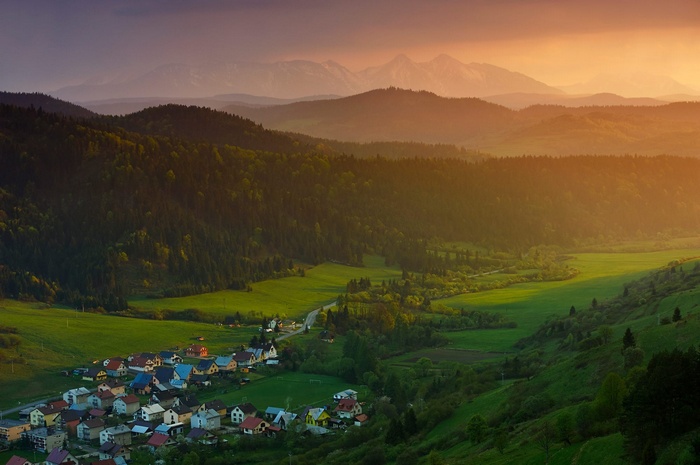 Village nestled in a valley with mountains at sunset