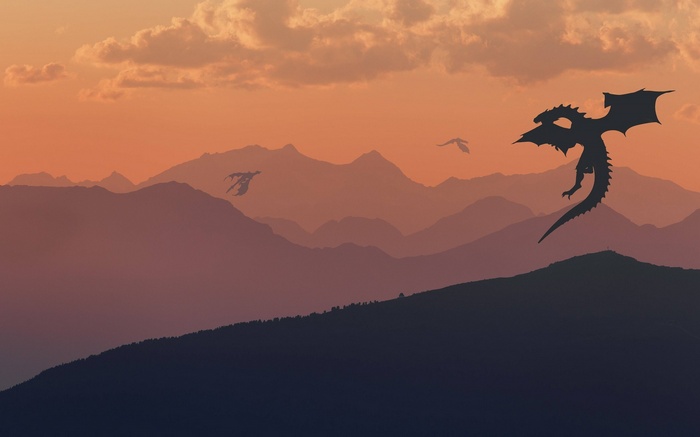 Dragons flying over mountains at sunset