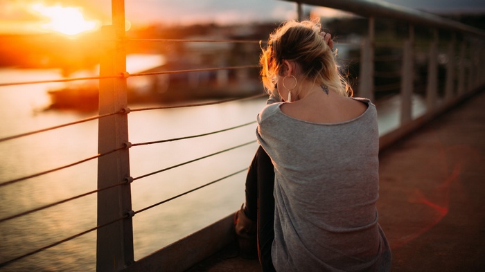 Woman sitting on a bridge at sunset