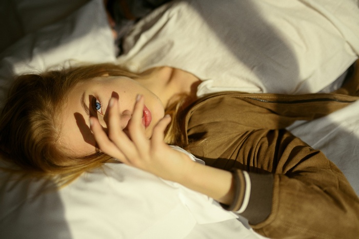 Woman with blonde hair and blue eyes in bed