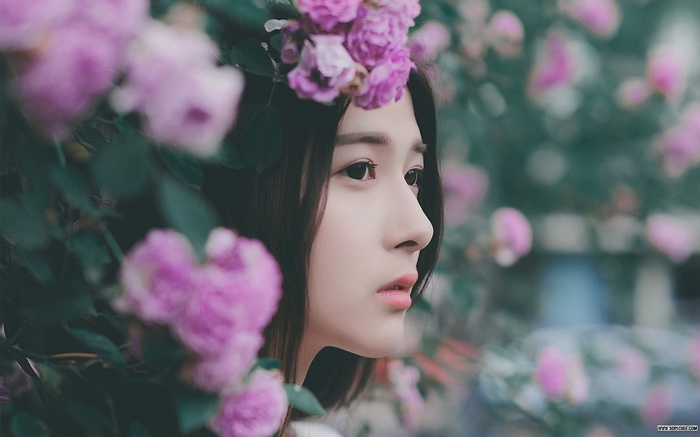 Young Asian woman with pink flowers in a garden