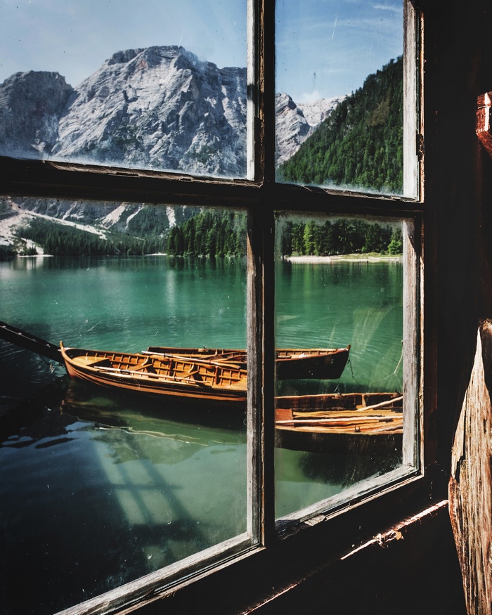 Boats on a lake with mountains and forest view through a window