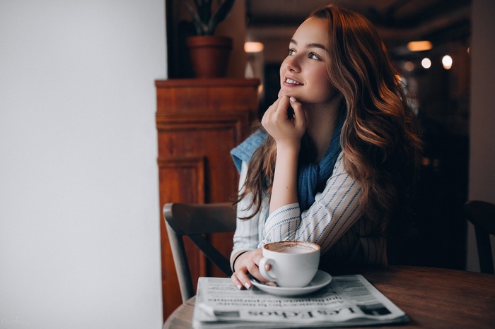 Woman with auburn hair at a cafe with coffee