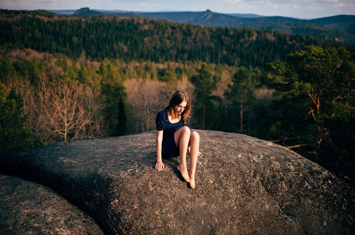 Woman sitting on a rock overlooking a forest