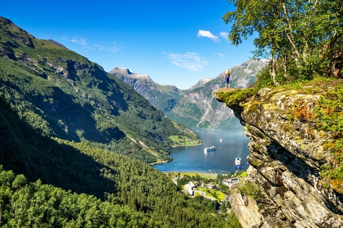 Woman on cliff overlooking Geiranger Fjord, Norway