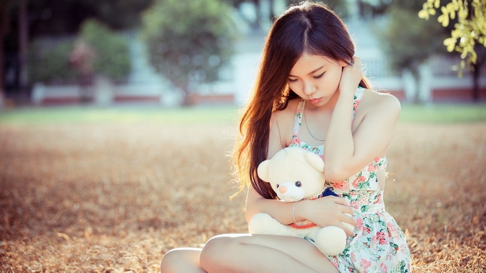 Young woman holding a teddy bear outdoors
