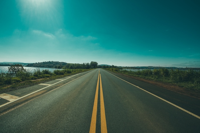 Road with yellow lines next to a body of water
