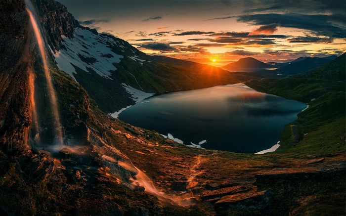 Sunset over a mountain lake with a waterfall