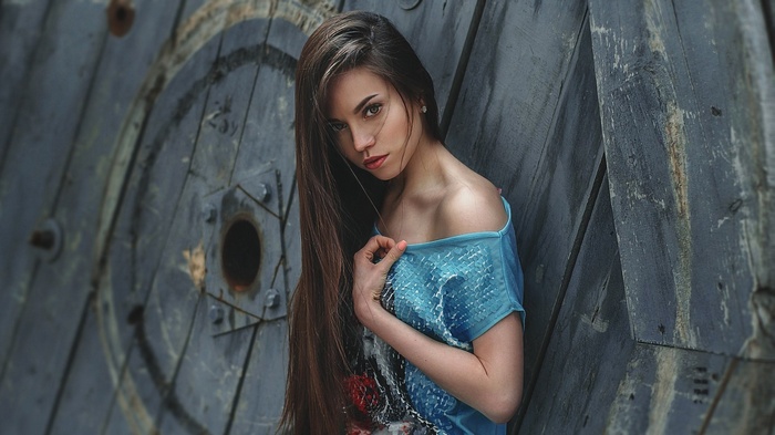 Woman with long hair leaning against a wooden structure
