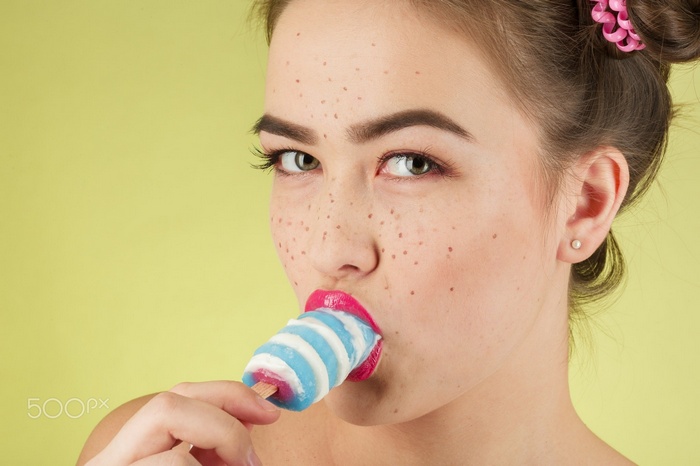 Woman with freckles eating a popsicle