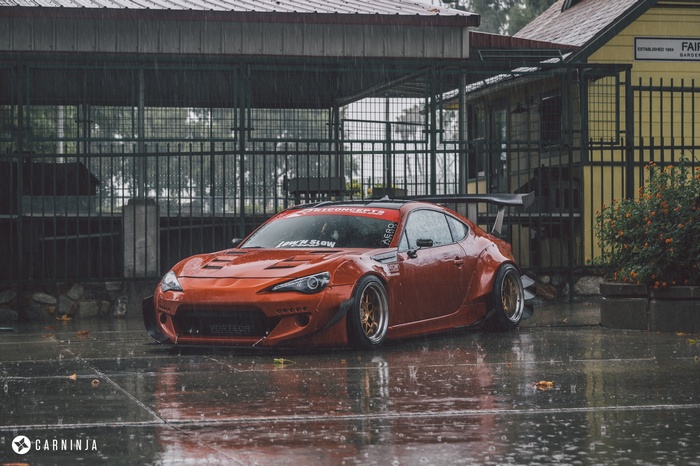 Orange widebody Toyota GT86 with large rear wing in rain