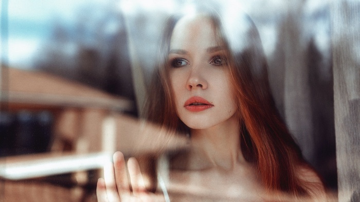 Woman with red hair looking through glass