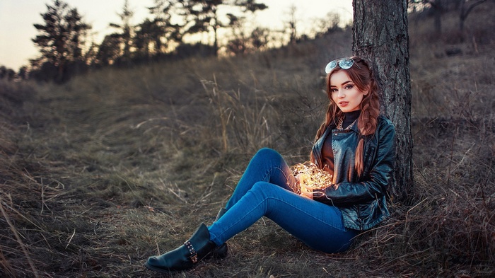 Woman sitting by a tree with fairy lights