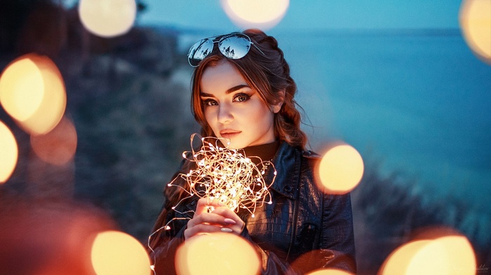 Woman holding string lights with sunglasses