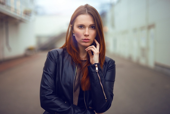 Woman with red hair wearing a leather jacket outdoors