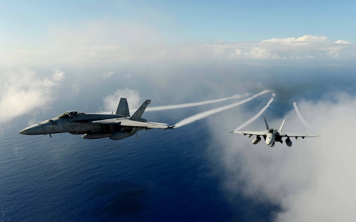 Two Boeing FA-18F Super Hornets fly over the ocean