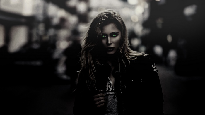 Woman with glowing green eyes in dark street