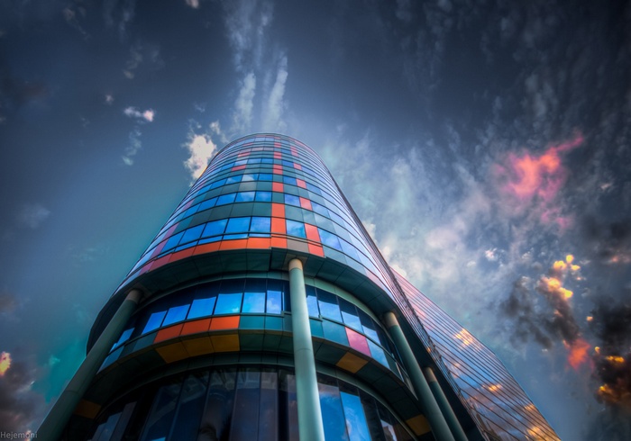 Modern glass building with colorful panels against a cloudy sky